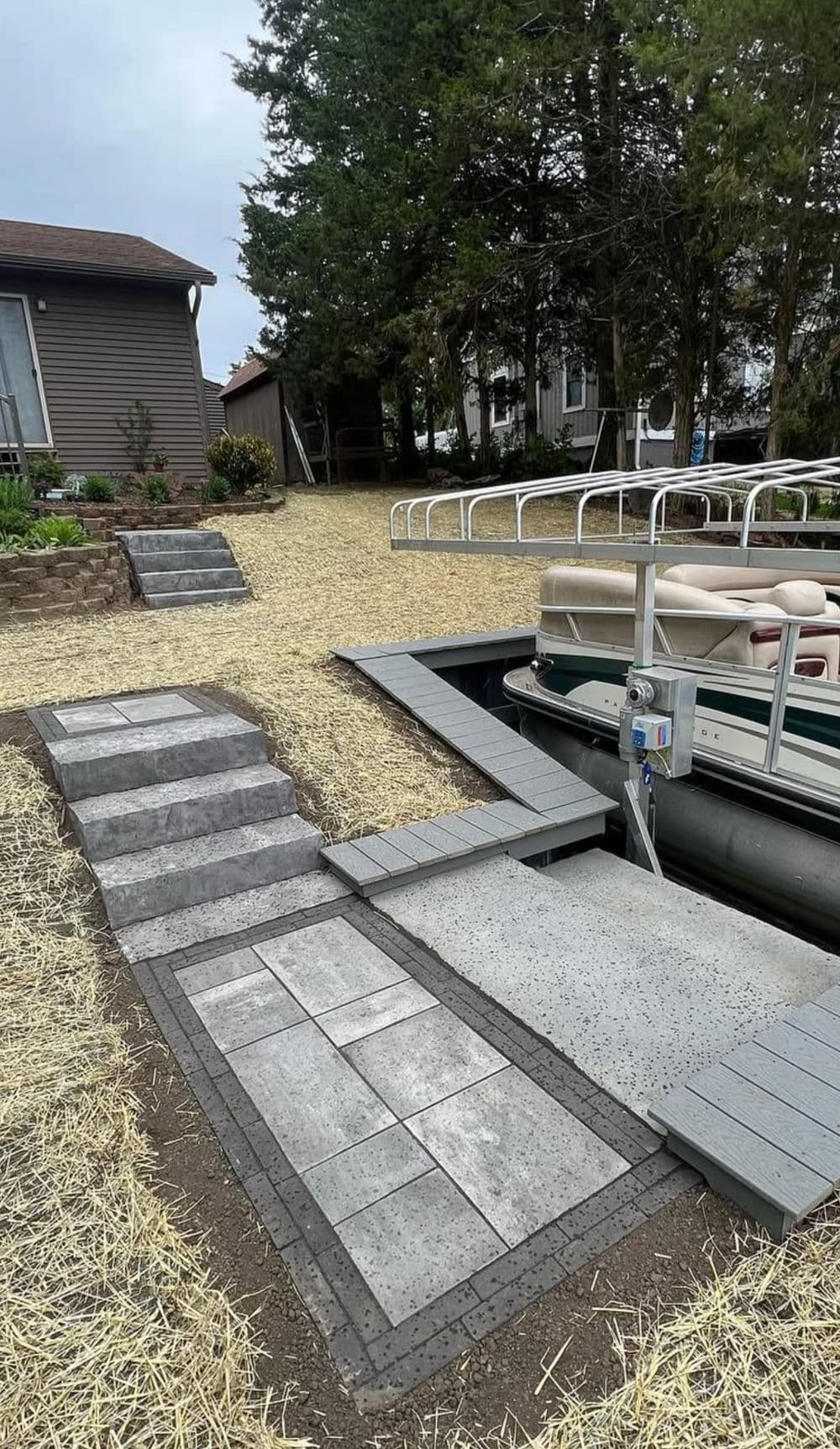 Stone pathway leading to a boat dock, surrounded by grass and trees for outdoor recreation.